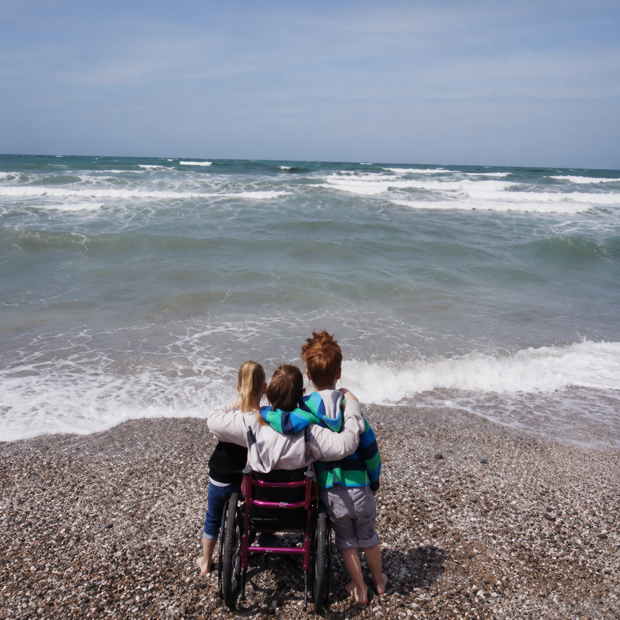 Familia usuaria de silla de ruedas frente al mar